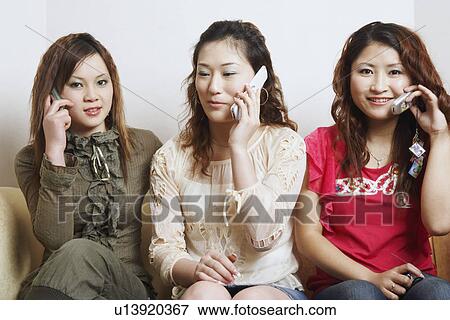 Stock Photo - Close-up of three young women talking on mobile phones. Fotosearch