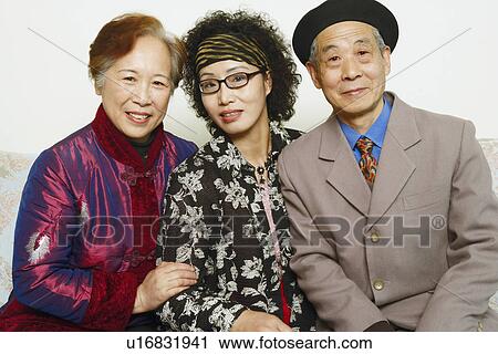 Stock Image - Portrait of a senior man sitting on a couch with two mature women. Fotosearch
