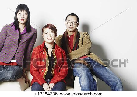 Portrait of a young man and two young women sitting on a couch View Large Photo Image Stock Photograph - Portrait of a young man and two young women sitting on a couch. Fotosearch