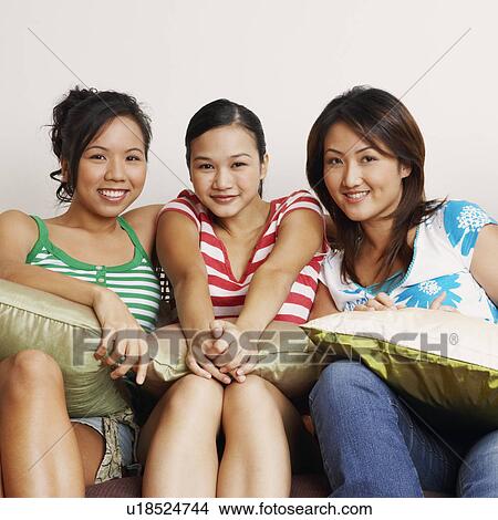 Portrait of four young women sitting on a couch and smiling View Large Photo Image Picture - Portrait of four young women sitting on a couch and smiling. Fotosearch