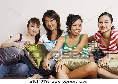 Portrait of four young women sitting on a couch and smiling View Large Photo Image Stock Photo - Portrait of four young women sitting on a couch and smiling. Fotosearch