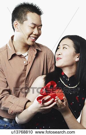 Stock Image - Close-up of a young couple holding a gift. Fotosearch