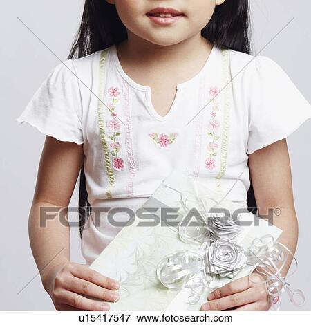 Portrait of a girl holding a gift and smiling View Large Photo Image Stock Photo - Portrait of a girl holding a gift and smiling. Fotosearch
