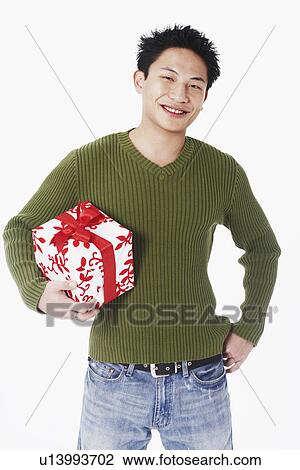 Stock Image - Portrait of a young man holding a gift. Fotosearch