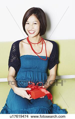 Portrait of a young woman holding a gift View Large Photo Image Picture - Portrait of a young woman holding a gift. Fotosearch