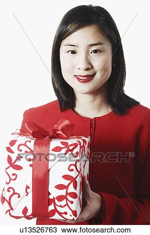 Stock Image - Portrait of a young woman holding a gift. Fotosearch
