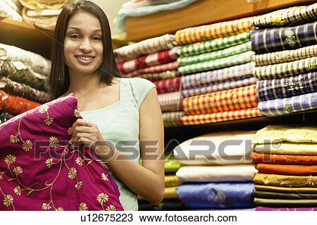Stock Image - Portrait of a young woman standing in a clothing store. Fotosearch