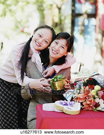Portrait of two young women holding a gift and smiling View Large Photo Image Stock Image - Portrait of two young women holding a gift and smiling. Fotosearch