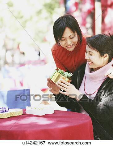 Two young women looking at a gift View Large Photo Image Stock Photo - Two young women looking at a gift. Fotosearch