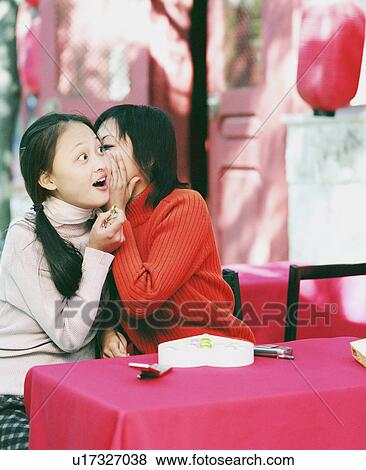Young woman whispering into another woman's ear View Large Photo Image Stock Photo - Young woman whispering into another woman's ear. Fotosearch