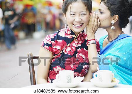 Close-up of a young woman whispering into another woman's ear View Large Photo Image Stock Photography - Close-up of a young woman whispering into another woman's ear. Fotosearch
