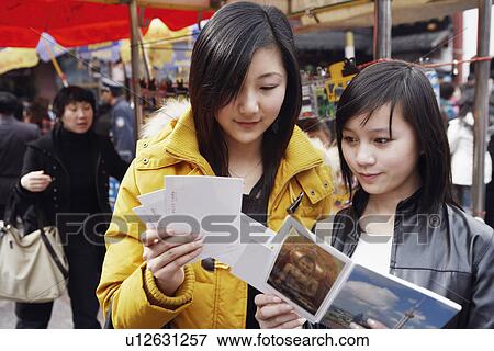 Stock Photo - Close-up of two young women holding postcards. Fotosearch