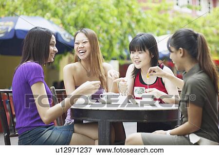 Four young women sitting in an outdoor restaurant View Large Photo Image Stock Photo - Four young women sitting in an outdoor restaurant. Fotosearch