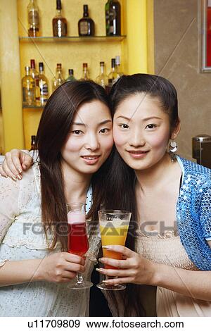 Stock Photo - Portrait of a teenage girl and a young woman holding drinks. Fotosearch