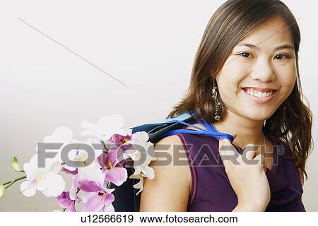Portrait of a young woman carrying flowers in a shopping bag View Large Photo Image Stock Photo - Portrait of a young woman carrying flowers in a shopping bag. Fotosearch