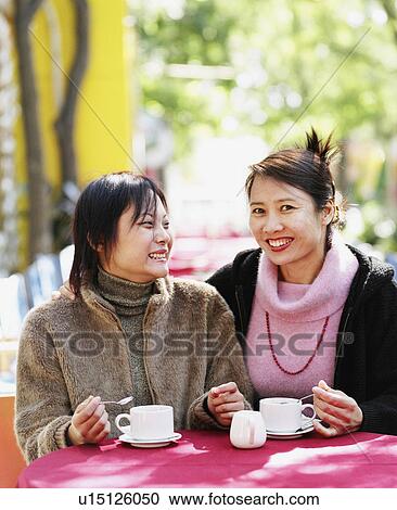 Portrait of a young woman sitting in a restaurant with another young woman View Large Photo Image Stock Image - Portrait of a young woman sitting in a restaurant with another young woman. Fotosearch