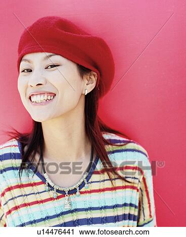 Stock Image - Portrait of a young woman wearing a cap and smiling. Fotosearch