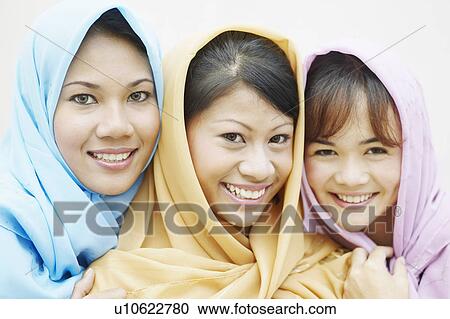 Stock Image - Portrait of three young women wearing scarves smiling. Fotosearch