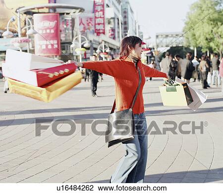 Young woman standing and swinging shopping bags View Large Photo Image Stock Image - Young woman standing and swinging shopping bags. Fotosearch