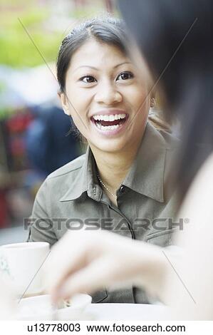Young woman talking to another woman and laughing View Large Photo Image Stock Image - Young woman talking to another woman and laughing. Fotosearch