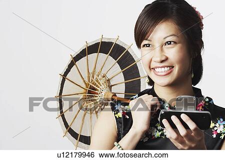 Stock Photograph - Close-up of a young woman holding a mobile phone and a parasol. Fotosearch