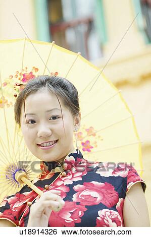 Stock Photograph - Low angle view of a young woman holding a parasol. Fotosearch