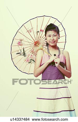 Portrait of a young woman holding a parasol and smiling View Large Photo Image Picture - Portrait of a young woman holding a parasol and smiling. Fotosearch