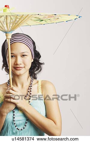 Picture - Portrait of a young woman holding a parasol and smiling. Fotosearch