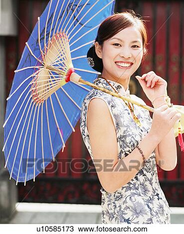 Stock Image - Portrait of a young woman holding a parasol. Fotosearch