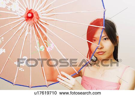 Stock Image - Portrait of a young woman holding a parasol. Fotosearch