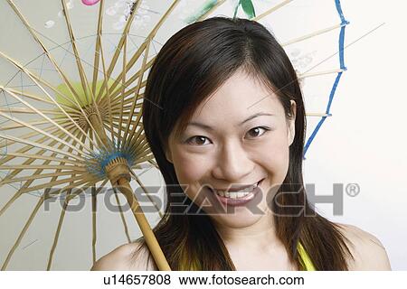 Stock Photo - Portrait of a young woman holding a parasol and smiling. Fotosearch