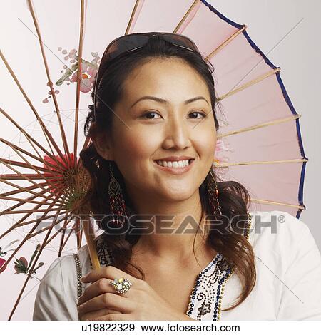 Stock Photo - Portrait of a young woman holding a parasol and smiling. Fotosearch