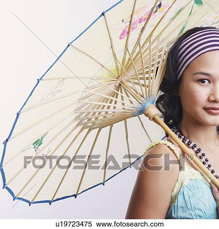 Stock Photography - Portrait of a young woman holding a parasol and smiling. Fotosearch