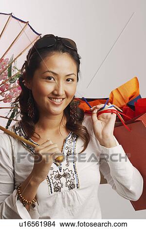 Picture - Portrait of a young woman holding shopping bags and smiling. Fotosearch