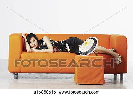 Stock Photography - Portrait of a young woman lying on a couch. Fotosearch