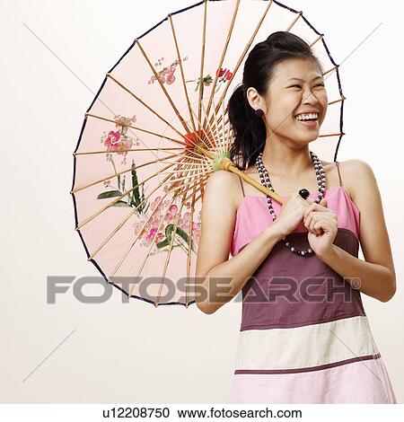 Young woman holding a parasol and smiling View Large Photo Image Stock Image - Young woman holding a parasol and smiling. Fotosearch