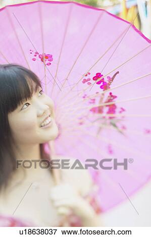 Stock Photo - Young woman holding a parasol smiling. Fotosearch