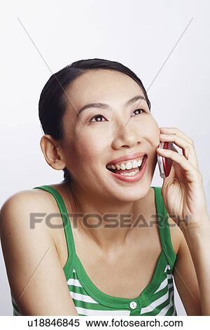 Stock Photography - Close-up of a mid adult woman talking on a mobile phone and laughing. Fotosearch