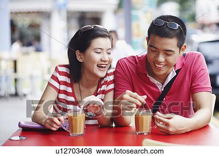 Close-up of a young couple sitting on the sidewalk cafe and smiling View Large Photo Image Stock Photo - Close-up of a young couple sitting on the sidewalk cafe and smiling. Fotosearch