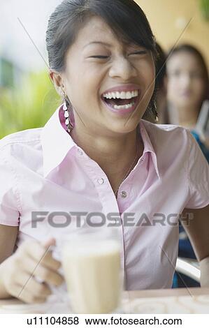 Stock Photo - Close-up of a young woman holding a milkshake. Fotosearch
