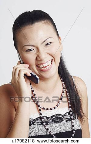 Stock Photo - Close-up of a young woman smiling and talking on a mobile phone. Fotosearch