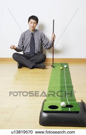 Stock Image - Portrait of a businessman sitting on the floor. Fotosearch