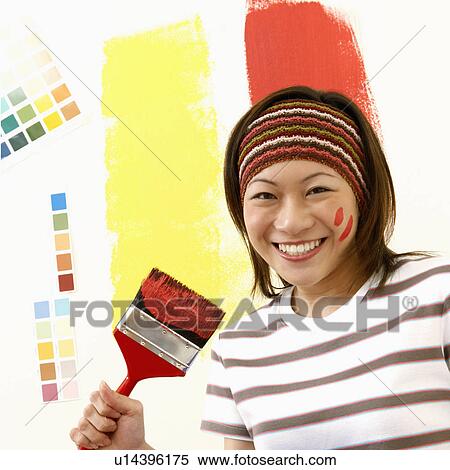 Stock Photography - Portrait of a young woman holding a paint tray with a paintbrush. Fotosearch