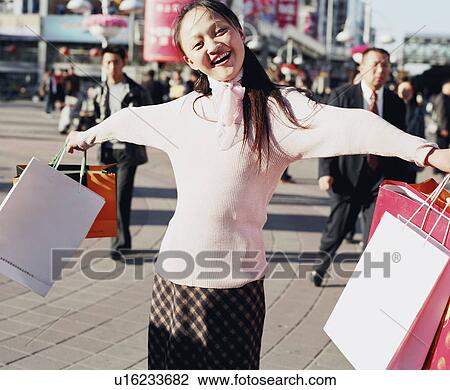 Stock Image - Portrait of a young woman holding shopping bags. Fotosearch