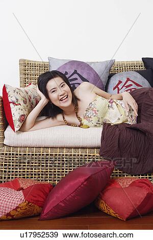 Portrait of a young woman lying on a couch and smiling View Large Photo Image Stock Photo - Portrait of a young woman lying on a couch and smiling. Fotosearch
