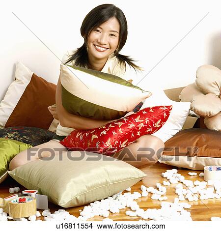 Portrait of a young woman sitting on the floor and hugging a cushion View Large Photo Image Picture - Portrait of a young woman sitting on the floor and hugging a cushion. Fotosearch