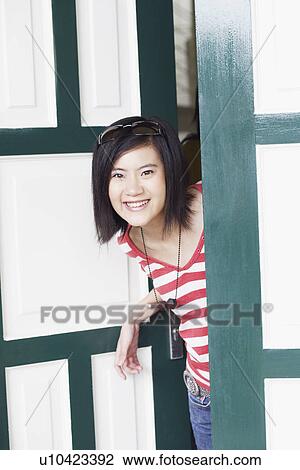 Portrait of a young woman smiling and standing at the door View Large Photo Image Stock Image - Portrait of a young woman smiling and standing at the door. Fotosearch