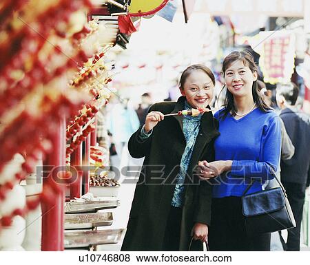 Portrait of a young woman standing with another woman in a street View Large Photo Image Stock Photo - Portrait of a young woman standing with another woman in a street. Fotosearch