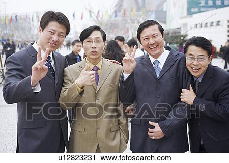 Stock Image - Portrait of four businessmen making hand signs. Fotosearch
