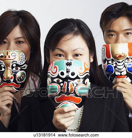 Picture - Portrait of two businesswomen and a businessman holding masks. Fotosearch